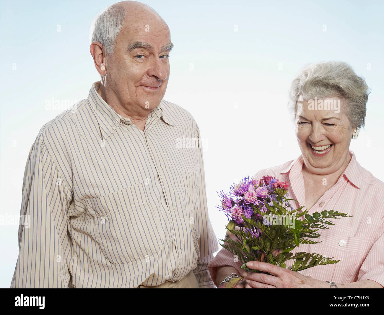 Ältere Mann weiß, dass sie glücklich ist, wenn er ihr Blumen schenkt Stockfoto