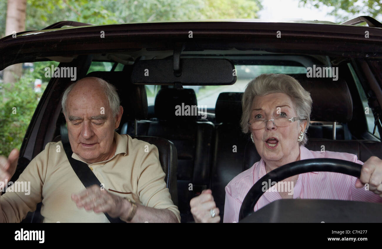 Frau fahren lernen aufgeregt während Mann in Beifahrer Sitz spricht für Ruhe Stockfoto