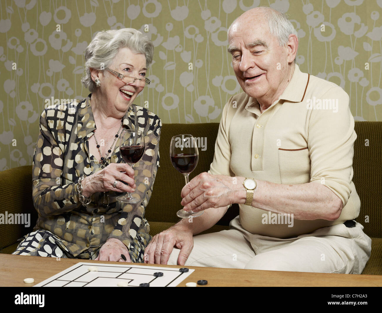 Älteres paar trinken Rotwein machen einen Toast auf der couch Stockfoto