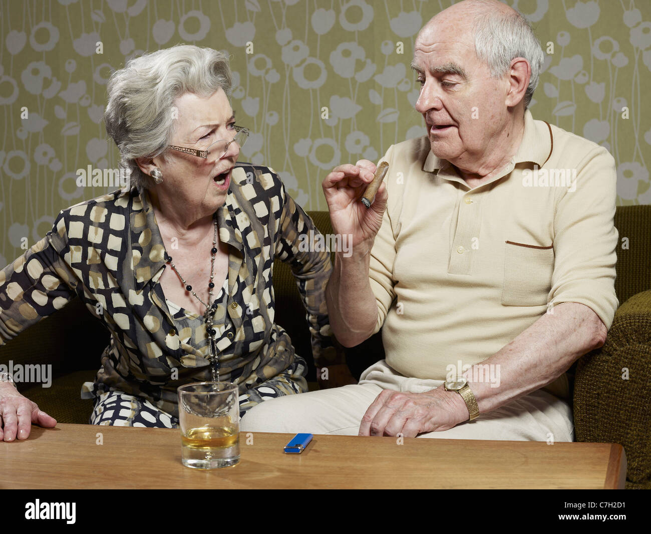 Ältere Frau sieht schockiert, als senior Mann Zigarre raucht Stockfoto