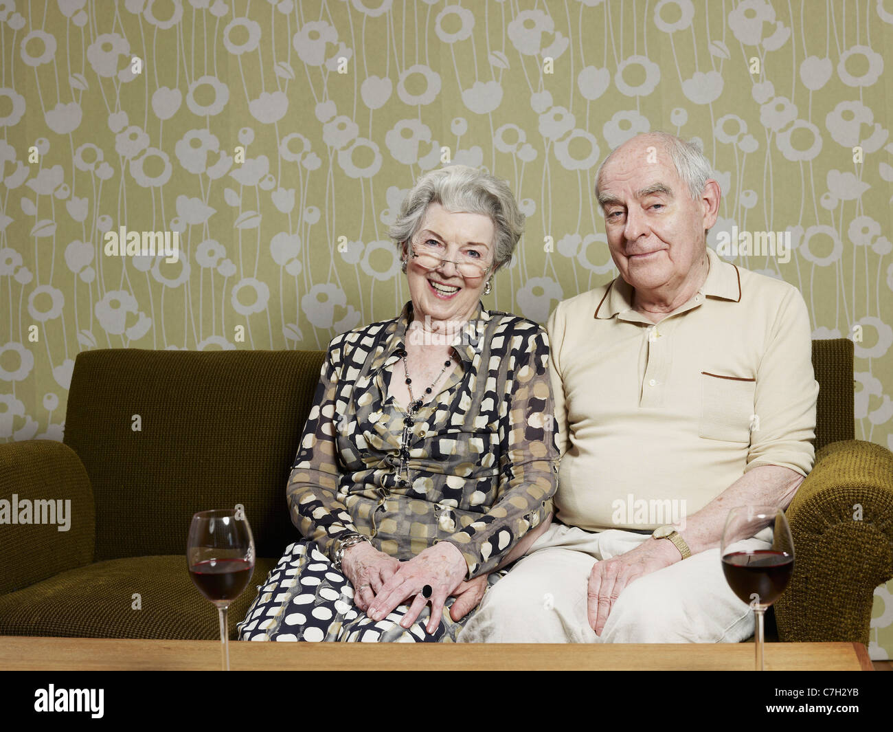 Mann und Frau entspannt auf dem Sofa, mit zwei Gläser Rotwein am Tisch vor Stockfoto