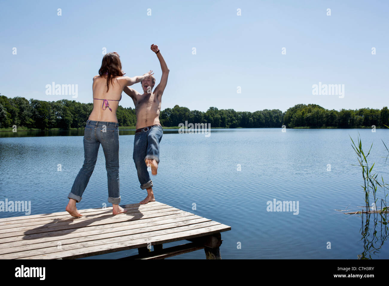 Mädchen am Steg drückt Mann ins Wasser Stockfotografie - Alamy