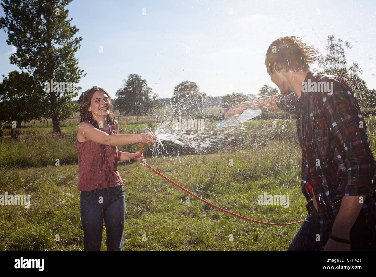 Mädchen-Sprays Kerl mit Schlauch in einem Feld Stockfoto