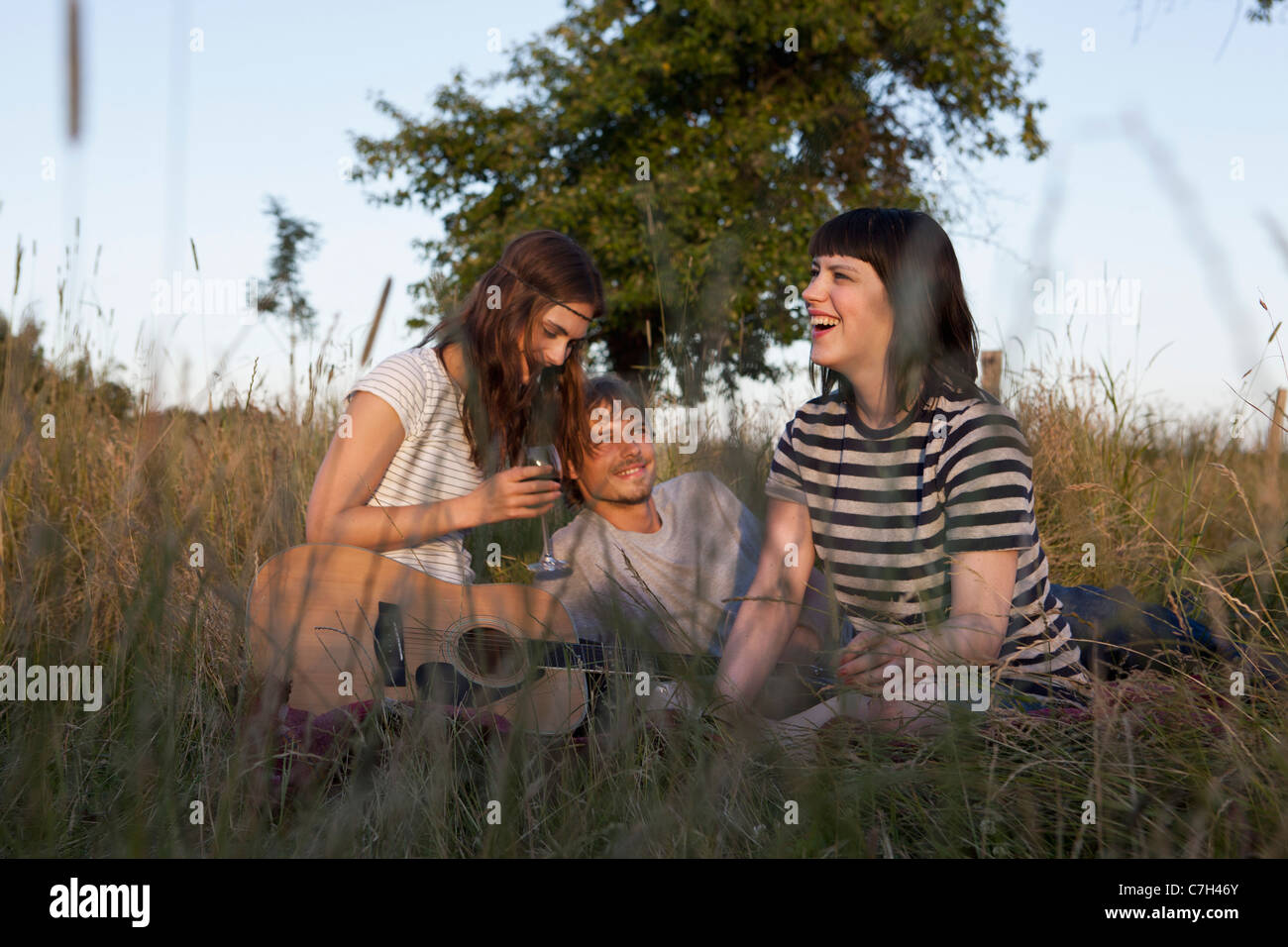 Drei Freunde genießen, sitzen auf abgelegenen Gebiet mit Wein und Gitarre Stockfoto