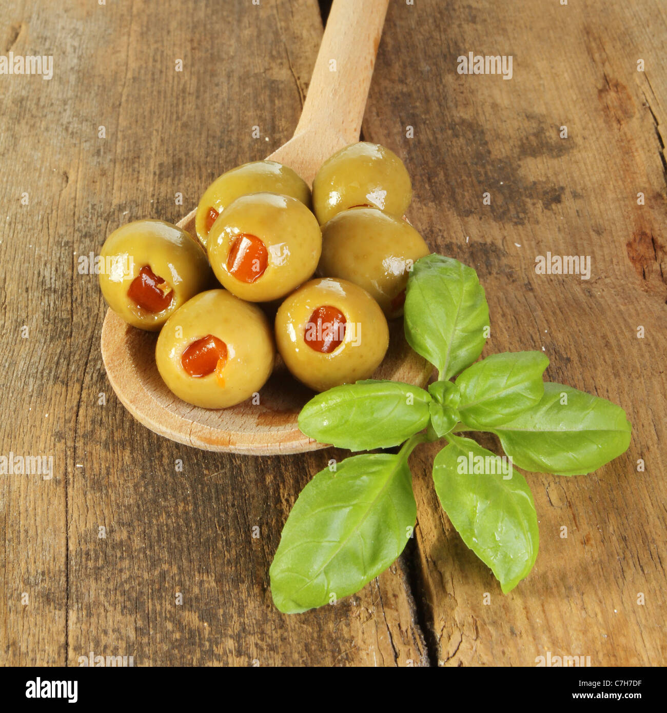 Oliven und Basilikum in einem Holzlöffel auf alte verwitterte Holz Stockfoto
