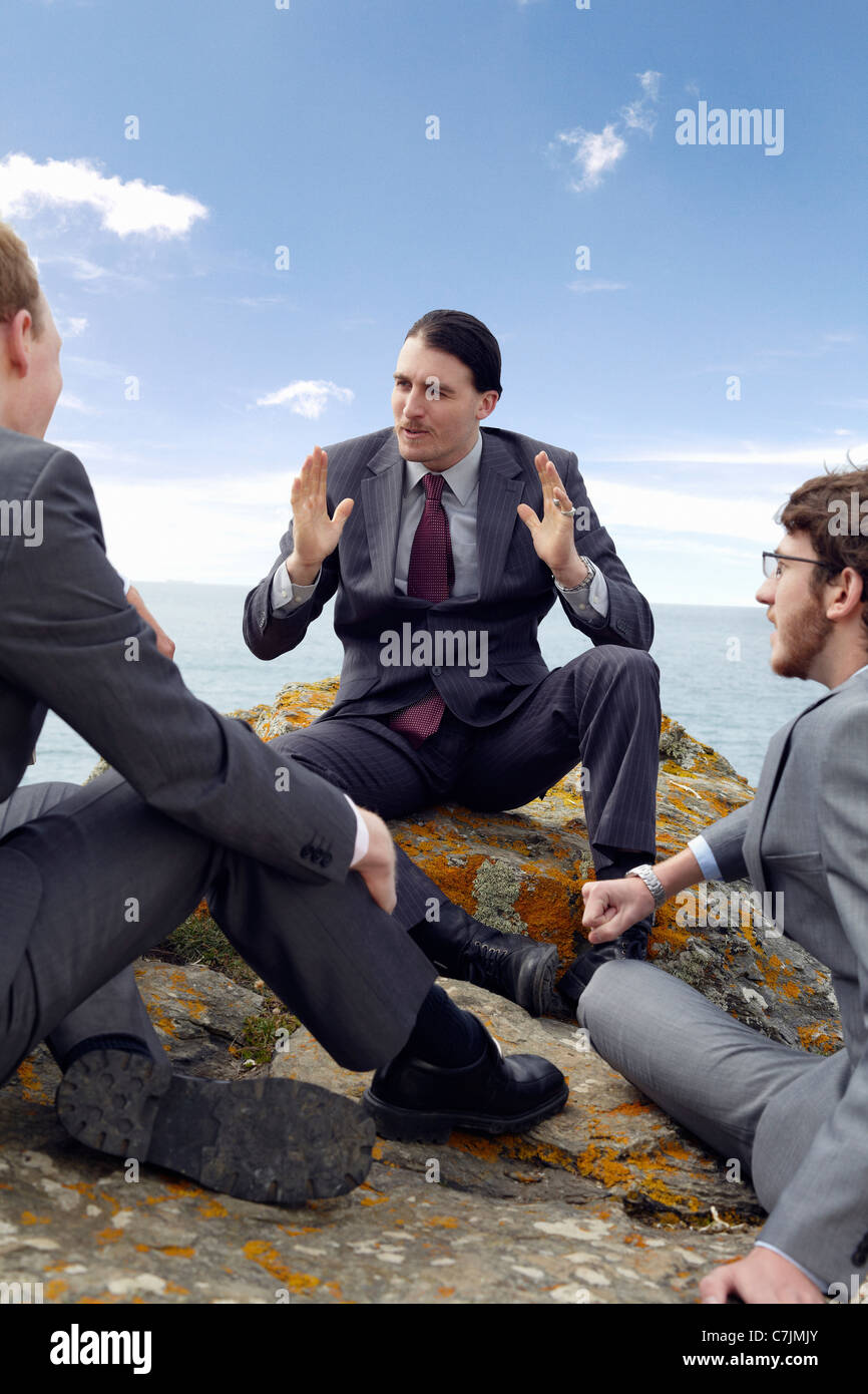 Geschäftsleute, die auf Felsen im Gespräch Stockfoto