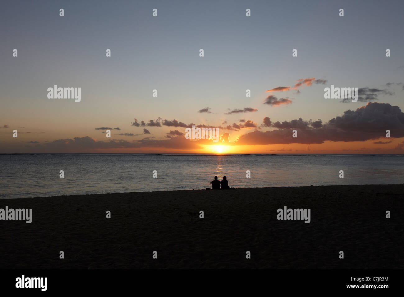 Paar sitzt am Strand bei Sonnenuntergang Stockfoto