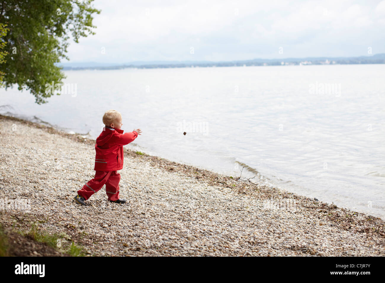 Junge wirft Felsen in See Stockfoto