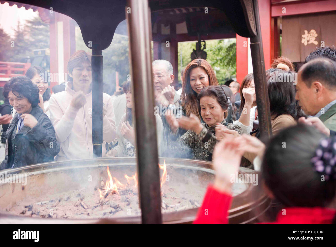 Besucher fanning Rauch von der brennenden Räucherstäbchen über sich selbst auf dem Vorplatz des Sensoji Tempels, Tokio Stockfoto