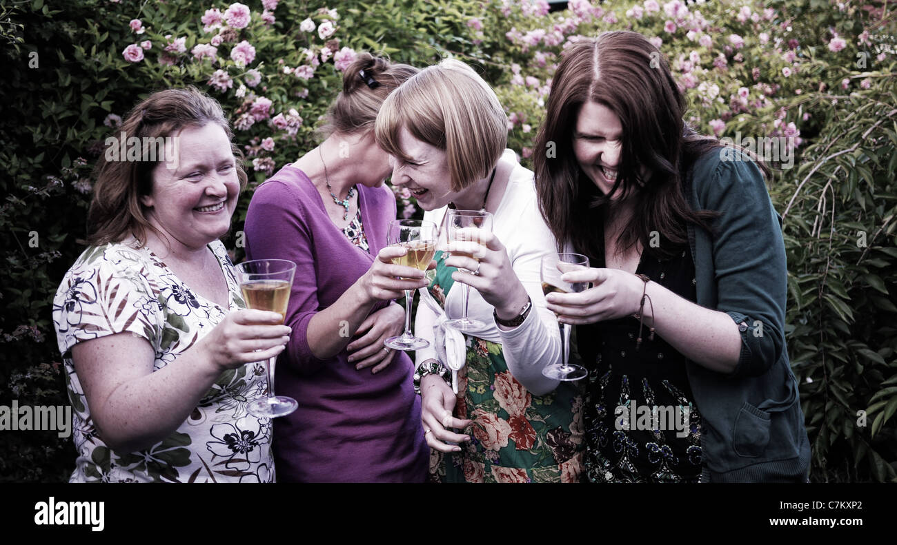 vier im mittleren Alter Damen Champagner trinken und lachen Stockfoto