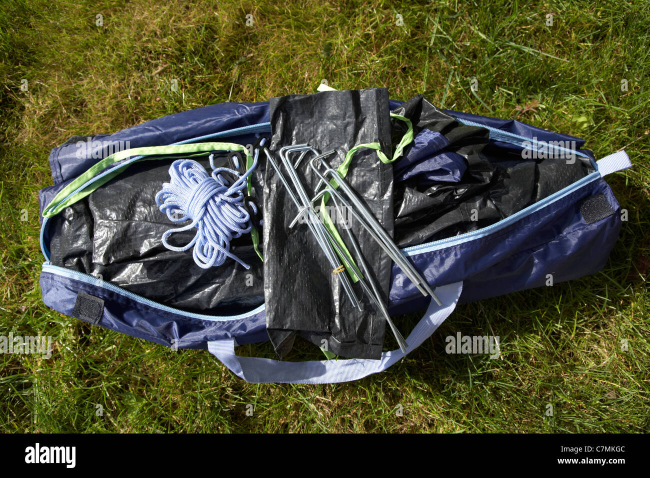 Beutel mit Heringen Auspacken ein kleines Zelt in einem Beutel auf dem Rasen liegend Stockfoto