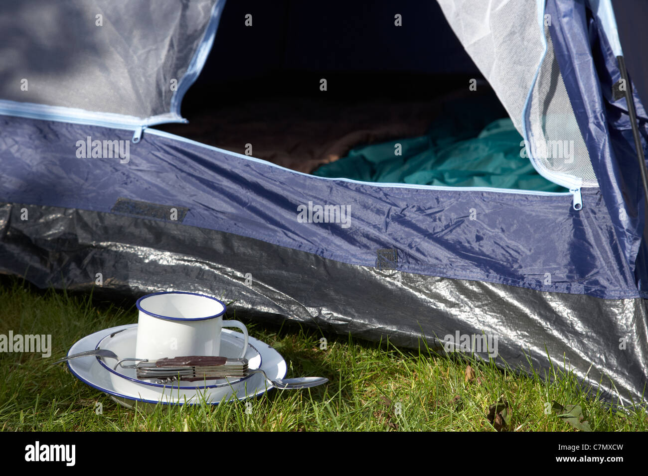 Weissblech Cup und camping-Werkzeug-Utensilien vor die offene Tür eines Zeltes Stockfoto