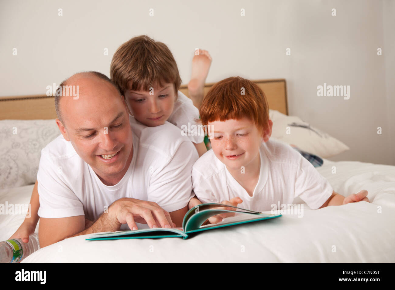Ein Vater und seine beiden Söhne gemeinsam lesen Stockfoto