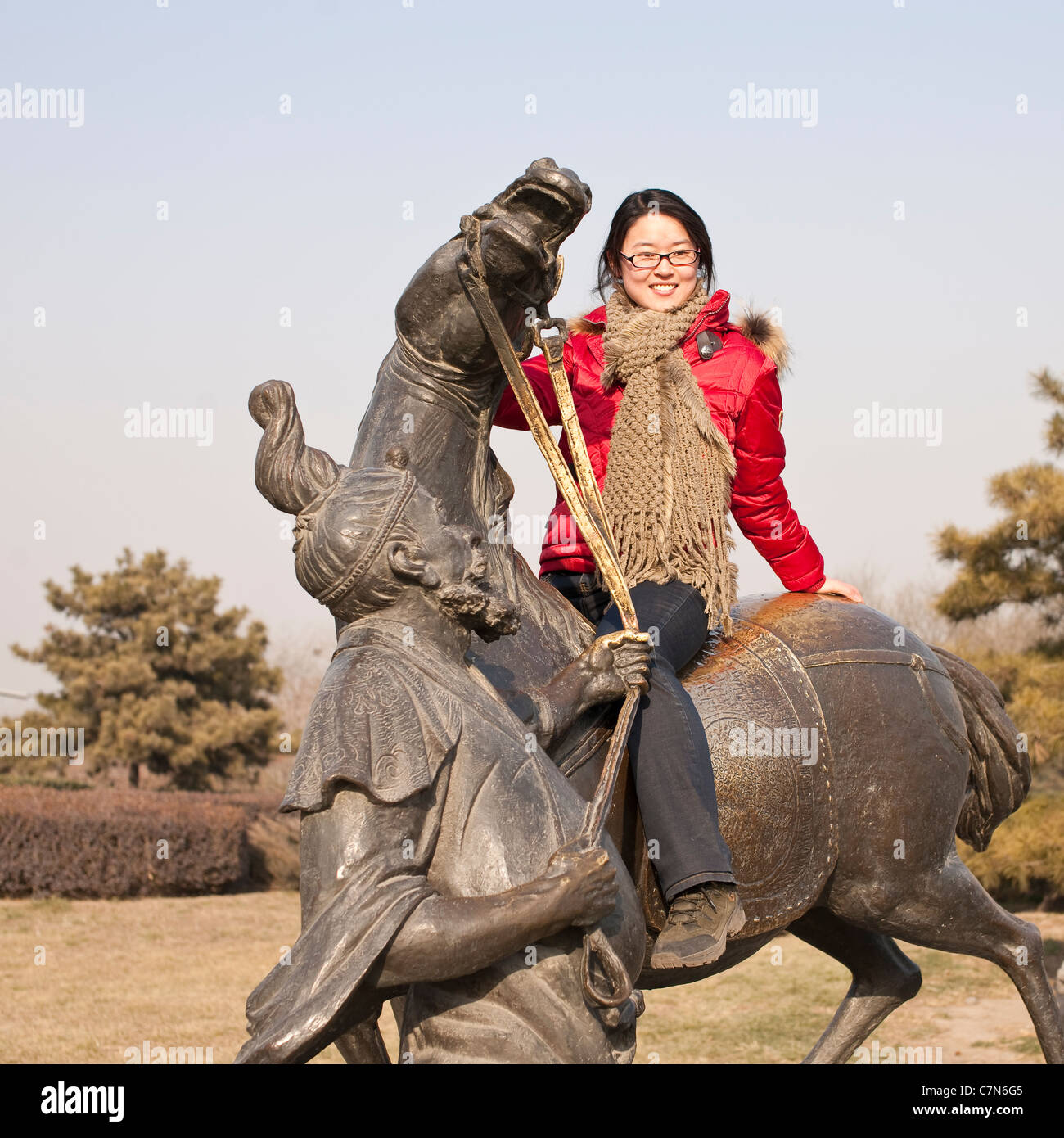 junge Chinesin Reittiere eine Pferd Statue im Park in der Nähe der Marco Polo-Brücke Stockfoto