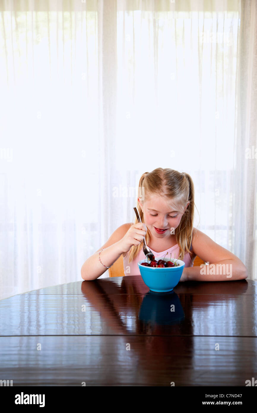 Kleines Mädchen aus einer Schüssel Kirschen essen Stockfoto