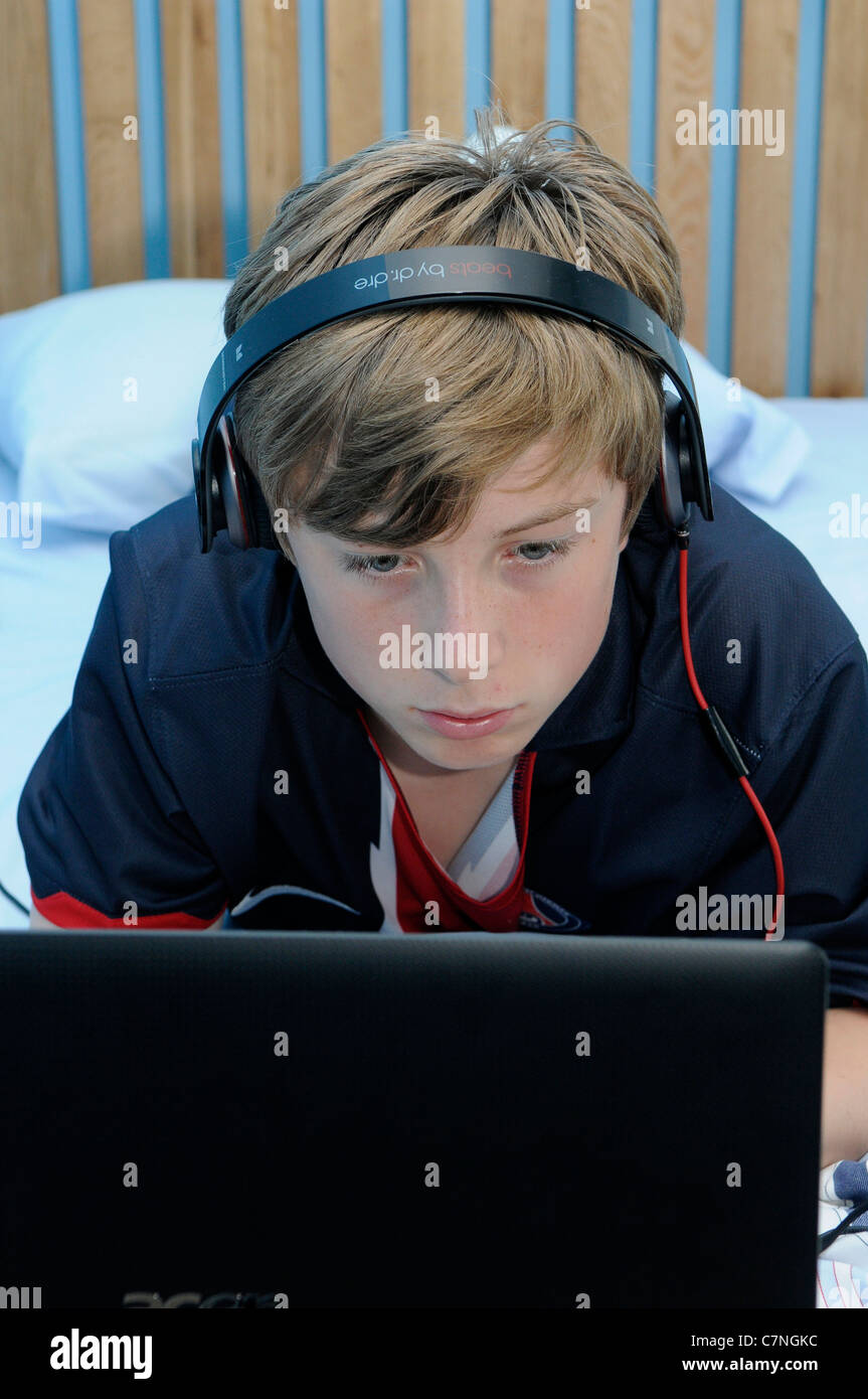 Junge von 13 Jahren mit Kopfhörer und laptop Stockfoto