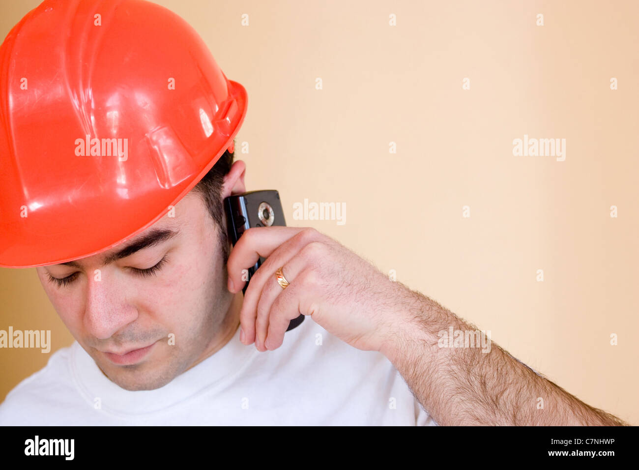 Ein junger Bauarbeiter spricht auf seinem Smartphone. Es gibt viele Exemplar für Ihren Text oder Bilder. Stockfoto