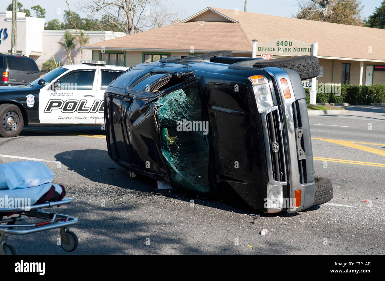 Umgestürzten Fahrzeug bei der Szene von einem Autounfall mit einem Polizeiwagen im Hintergrund Stockfoto