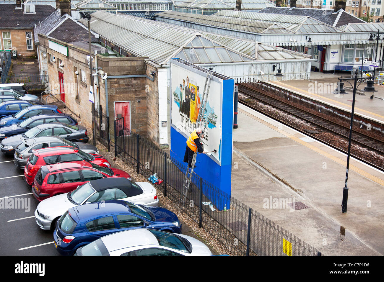 Bill Plakat setzen, ragte Werbeschild an Bord außen Stirling Bahnhof auf Leiter gegen gefährliche Horten Stockfoto