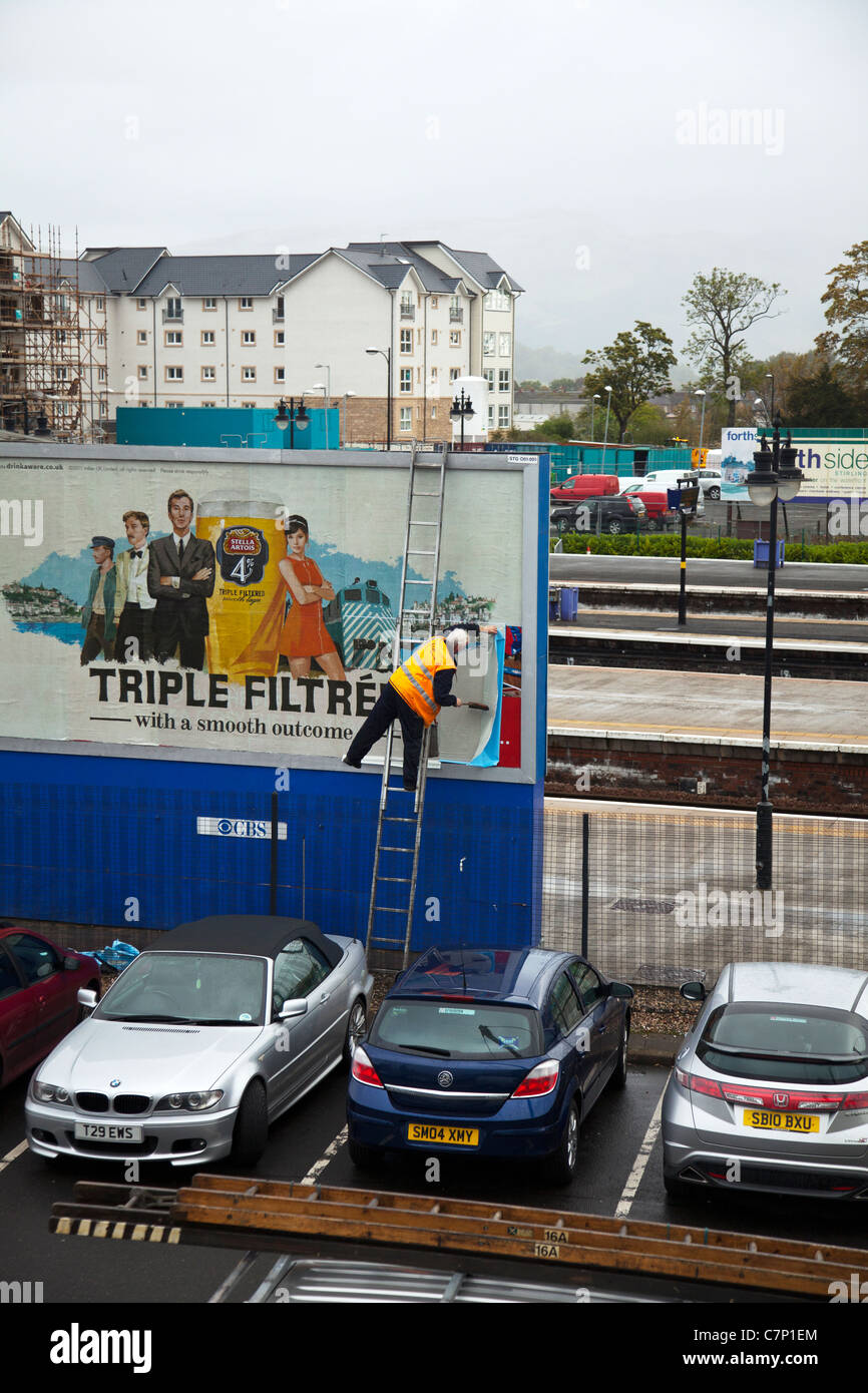 Bill Plakat setzen, ragte Werbeschild an Bord außen Stirling Bahnhof auf Leiter gegen gefährliche Horten Stockfoto