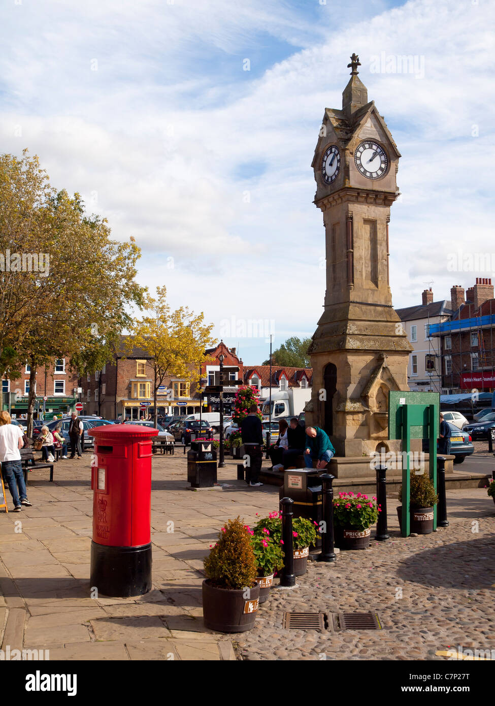 Die Stadt-Uhr und einen leuchtend roten Briefkasten auf dem Marktplatz in Thirsk North Yorkshire UK Stockfoto