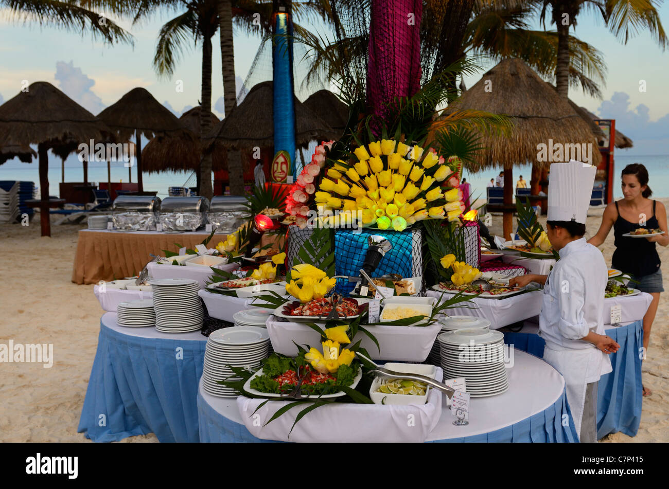 Abendbuffet mit strohgedeckten Sonnenschirmen am Strand in einem Luxus-Resort in Maya-Riviera-Mexiko Stockfoto