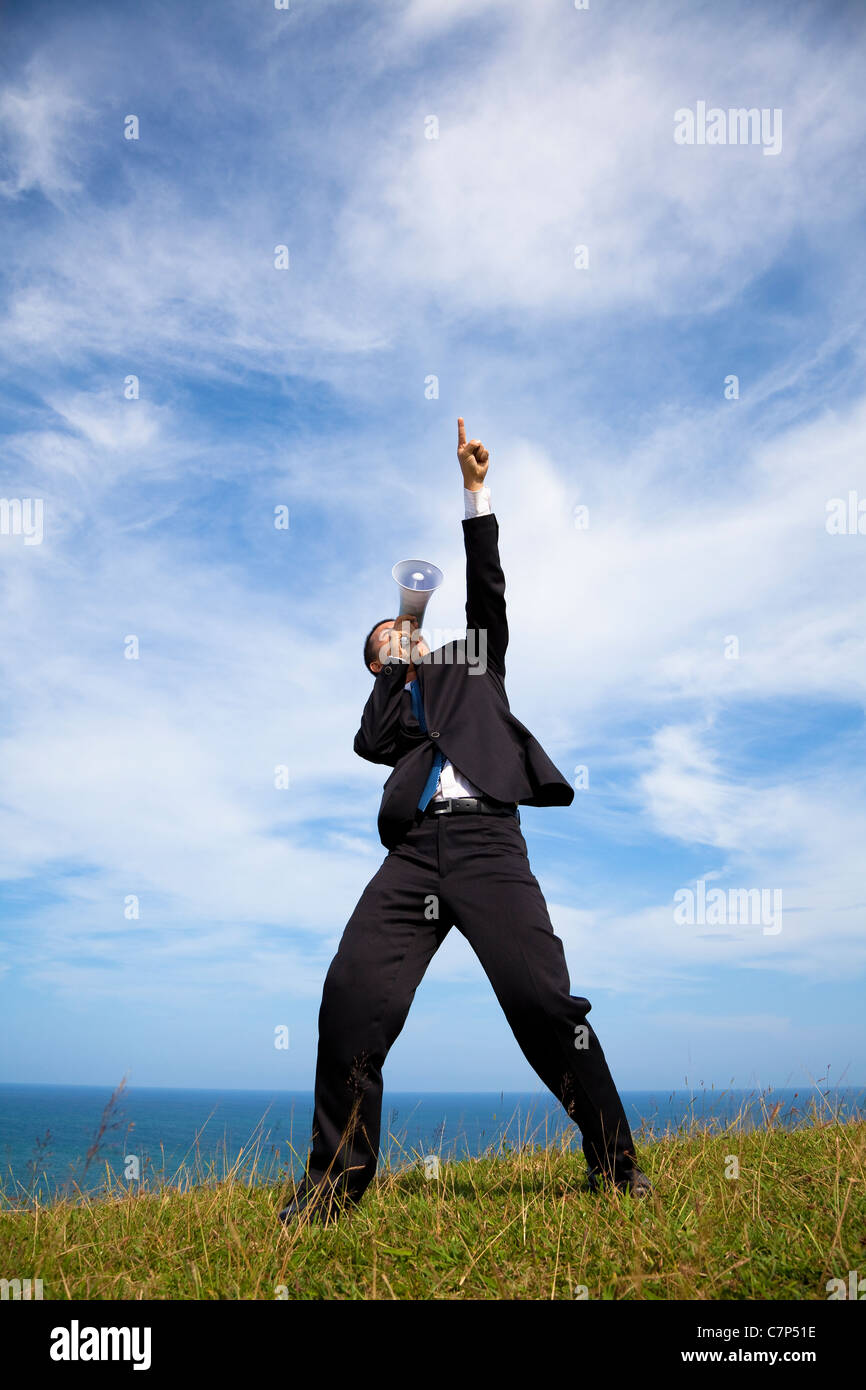 Geschäftsmann Stand auf dem Hügel und mit Megaphon mit Cloud-Hintergrund Stockfoto