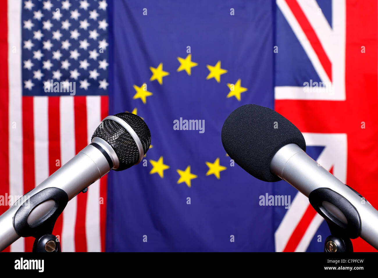 Zwei Mikrofone auf der Bühne eine Pressekonferenz mit den Flaggen aus Amerika, Europäische Union und dem Vereinigten Königreich Stockfoto