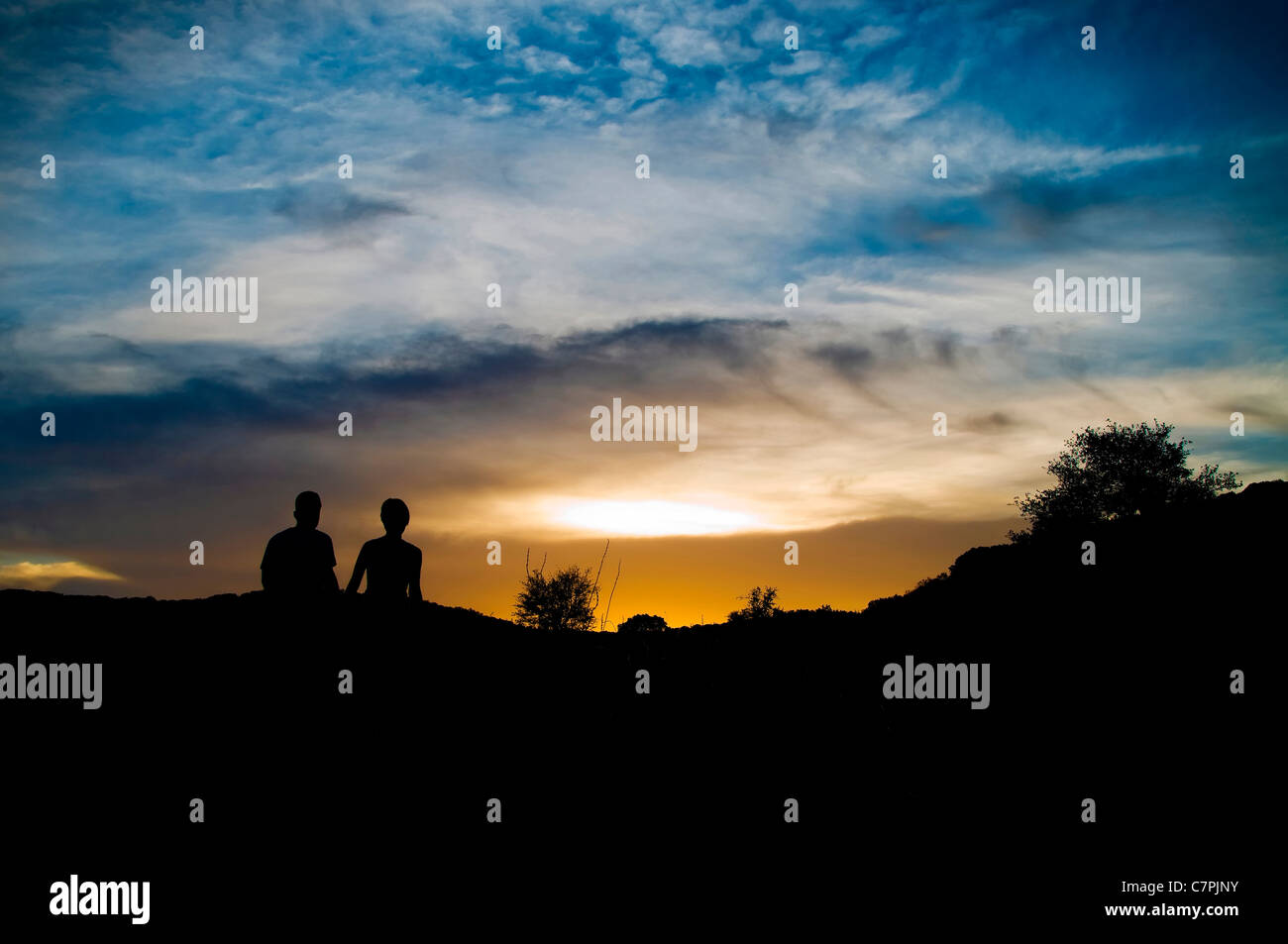 Silhouette eines jungen Paares in der Liebe zu Fuß in den Sonnenuntergang mit dramatischen Himmel. Stockfoto