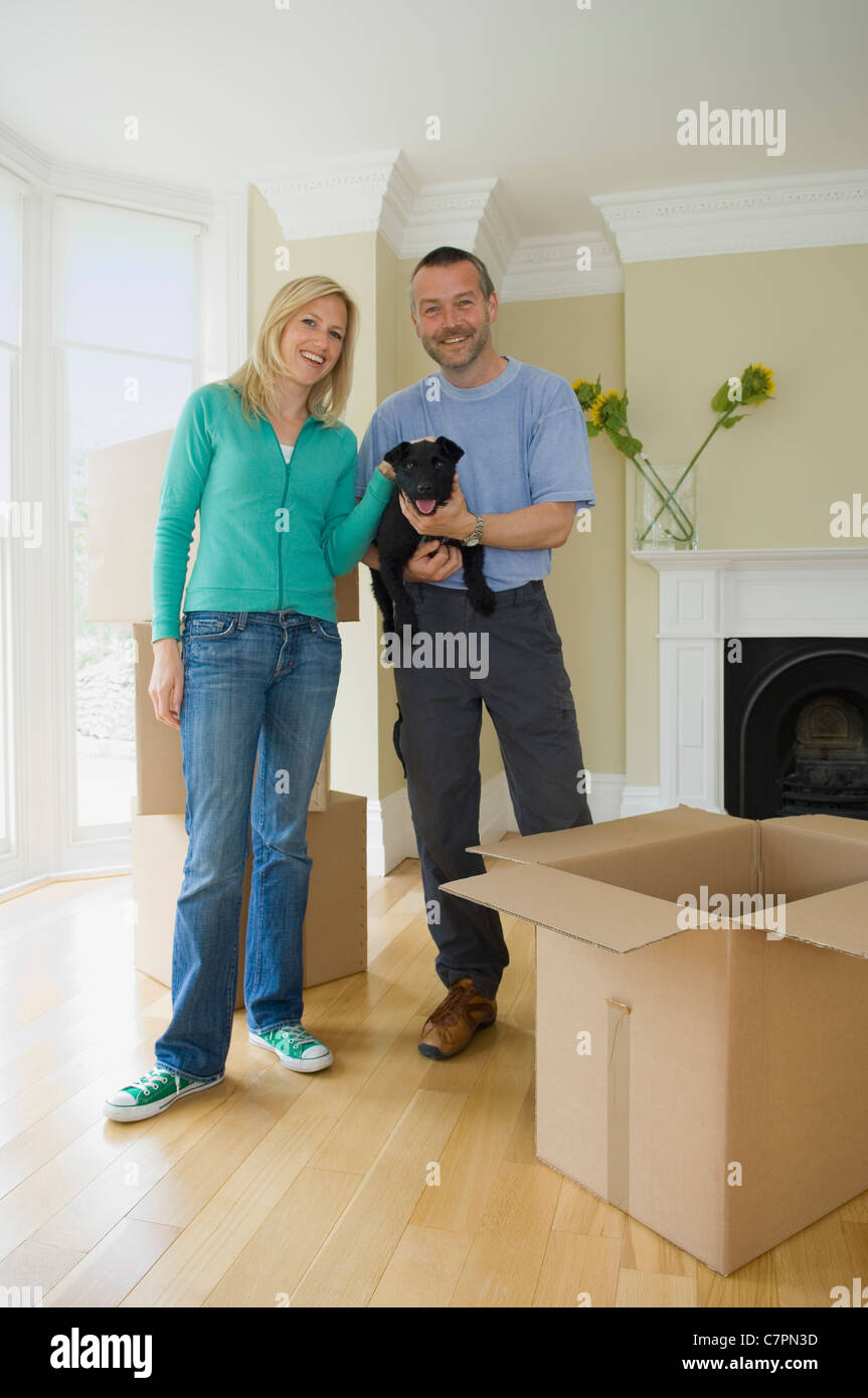 Lächelnde paar mit Hund im neuen Zuhause Stockfoto