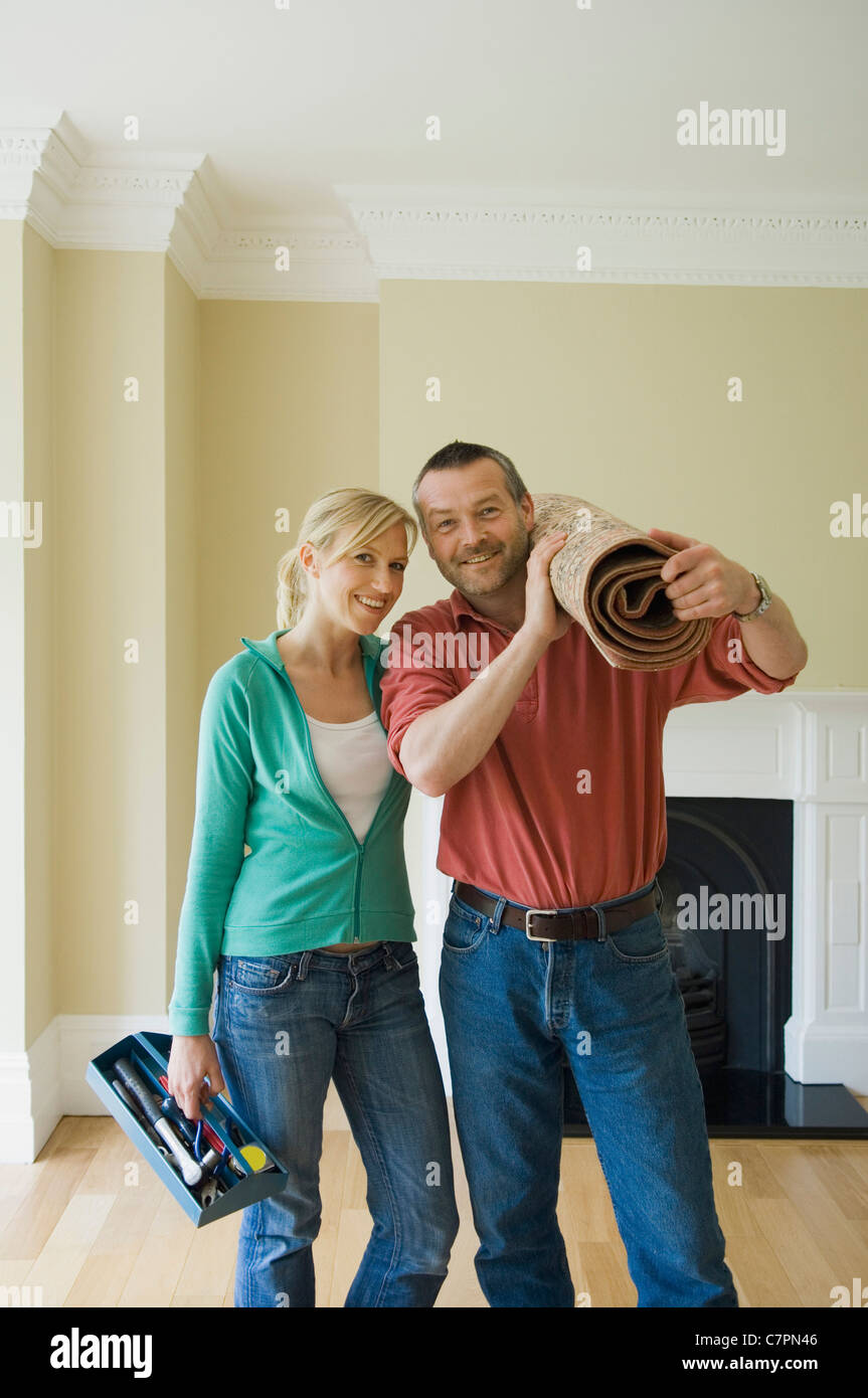 Paar mit gerollt Teppich im neuen Zuhause Stockfoto