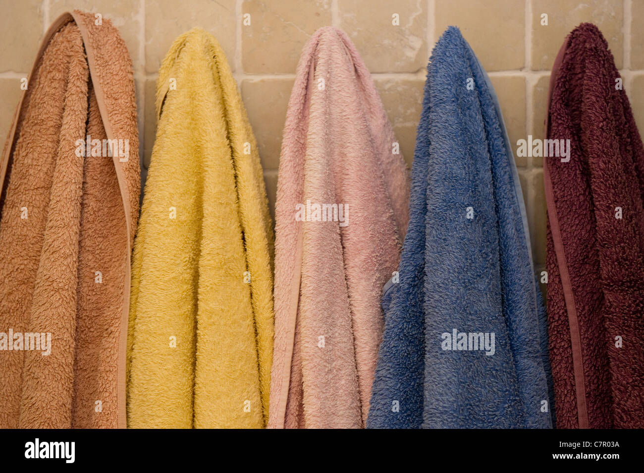 Eine Reihe von farbigen Handtücher hängen in einem Badezimmer Stockfoto