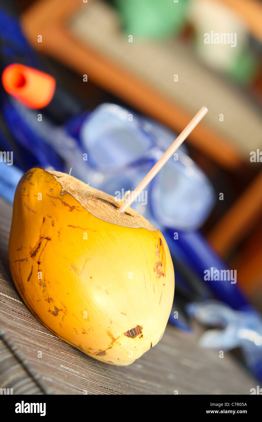 Kokosnuss mit Stroh und Schnorchel Ausrüstung im Hintergrund. Stockfoto