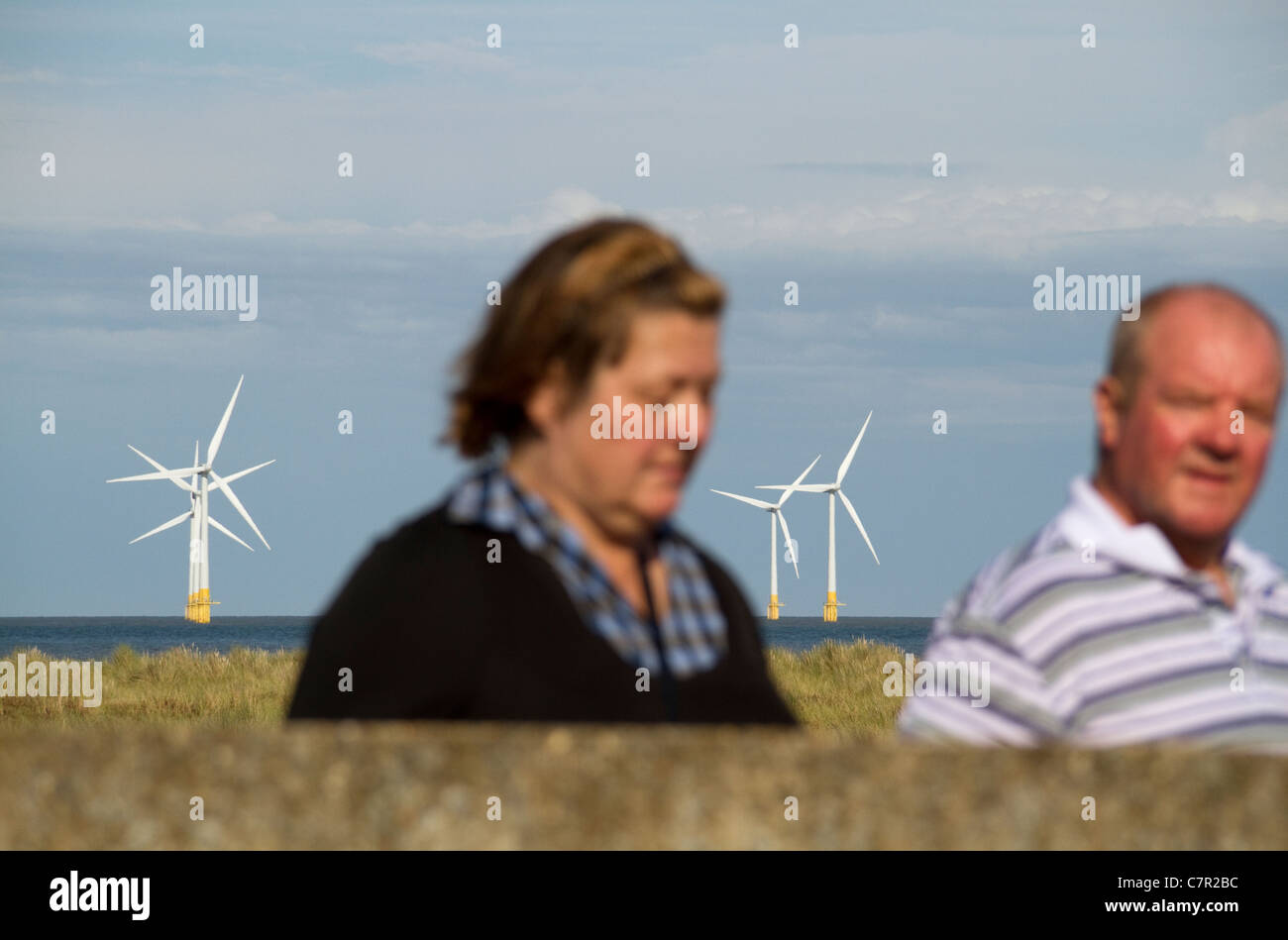 Offshore-Windenergieanlagen im Windpark vor Great Yarmouth Scroby Küste mit Mann und Frau im Vordergrund Stockfoto