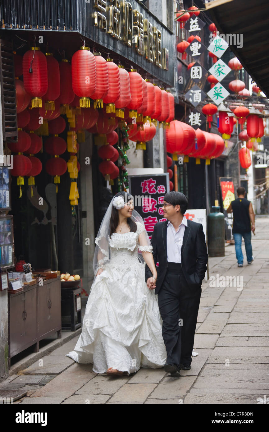 Frisch vermählte in Hochzeitskleid Bummeln auf gepflasterten Straße mit alten Residenz, Xitang, Zhejiang Province, China Stockfoto
