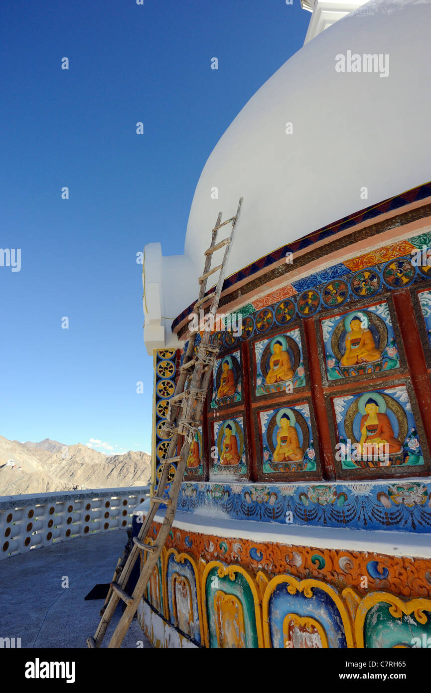 Eine Leiter lehnt sich an die Kuppel des Shanti Stupa. Platten, die Darstellung des Buddha und Monster Masken oder das Gesicht der Majestät Stockfoto