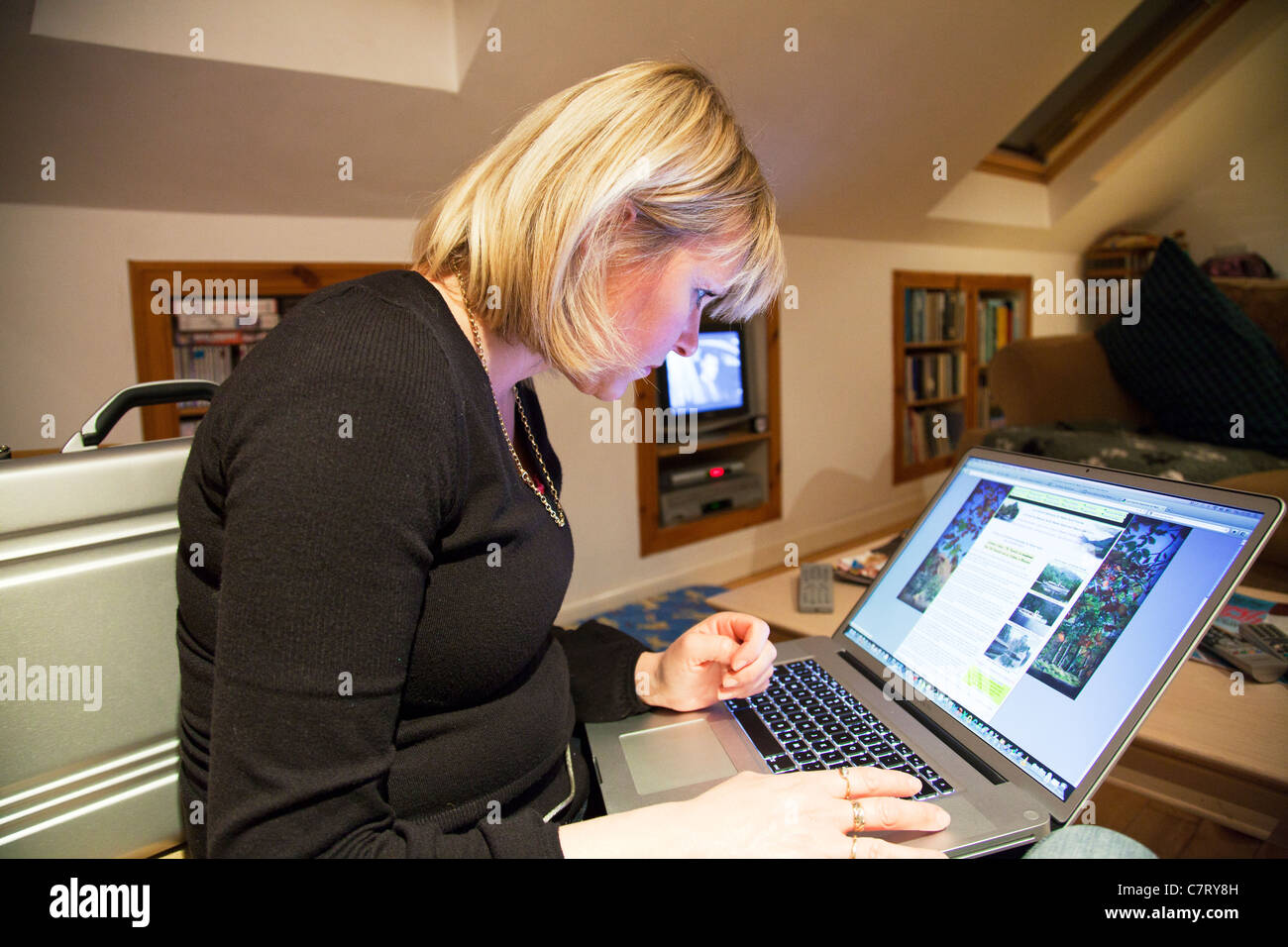 Dame mit Apple Mac Book pro Laptop zum Surfen im Internet am heimischen Fernseher auf im Hintergrund Seite entspannende anzeigen Stockfoto