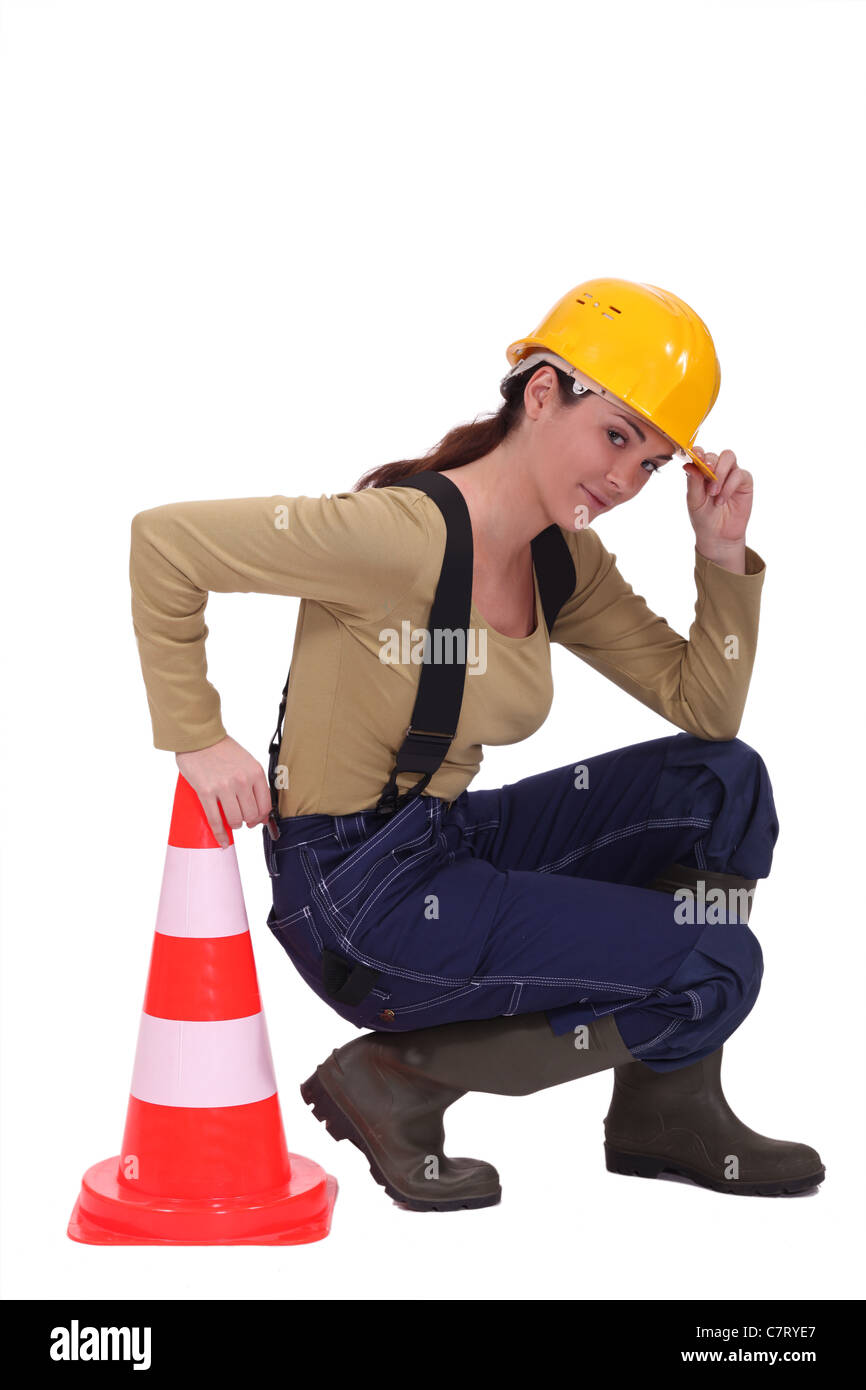 Handwerkerin kniend neben einem Verkehr Kegel Stockfoto
