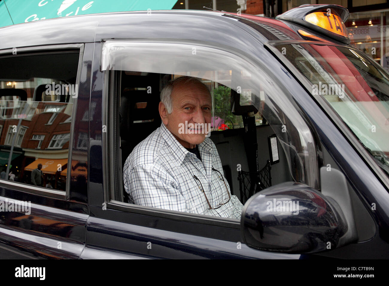 Ältere London Taxi-Fahrer in seinem Fahrzeug sitzen und warten auf einen Tarif. Stockfoto