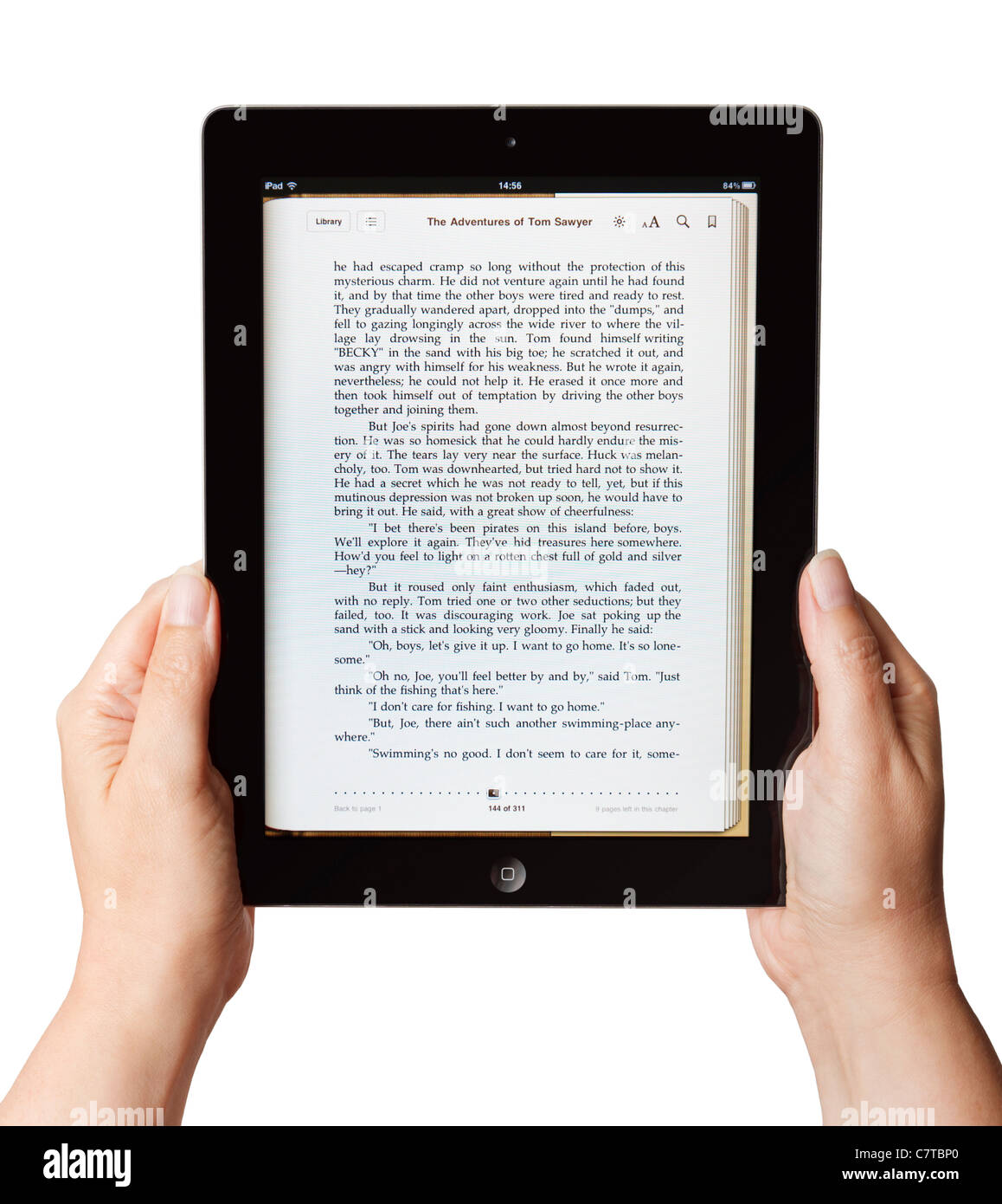 Weibliche Hände halten ein altes iPad und lesen ein Buch Stockfoto