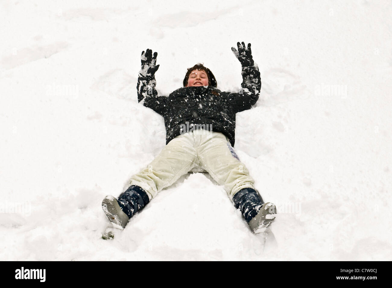 Junge liegend im Schnee Stockfoto