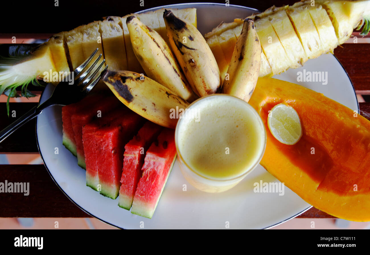 Tagesbedarf gesunde frische Früchte, Ananas, Wassermelone, Paw Paw, Papaya, Bananen Fruchtsaft auf einer Goldschnitt Teller Gabel Stockfoto