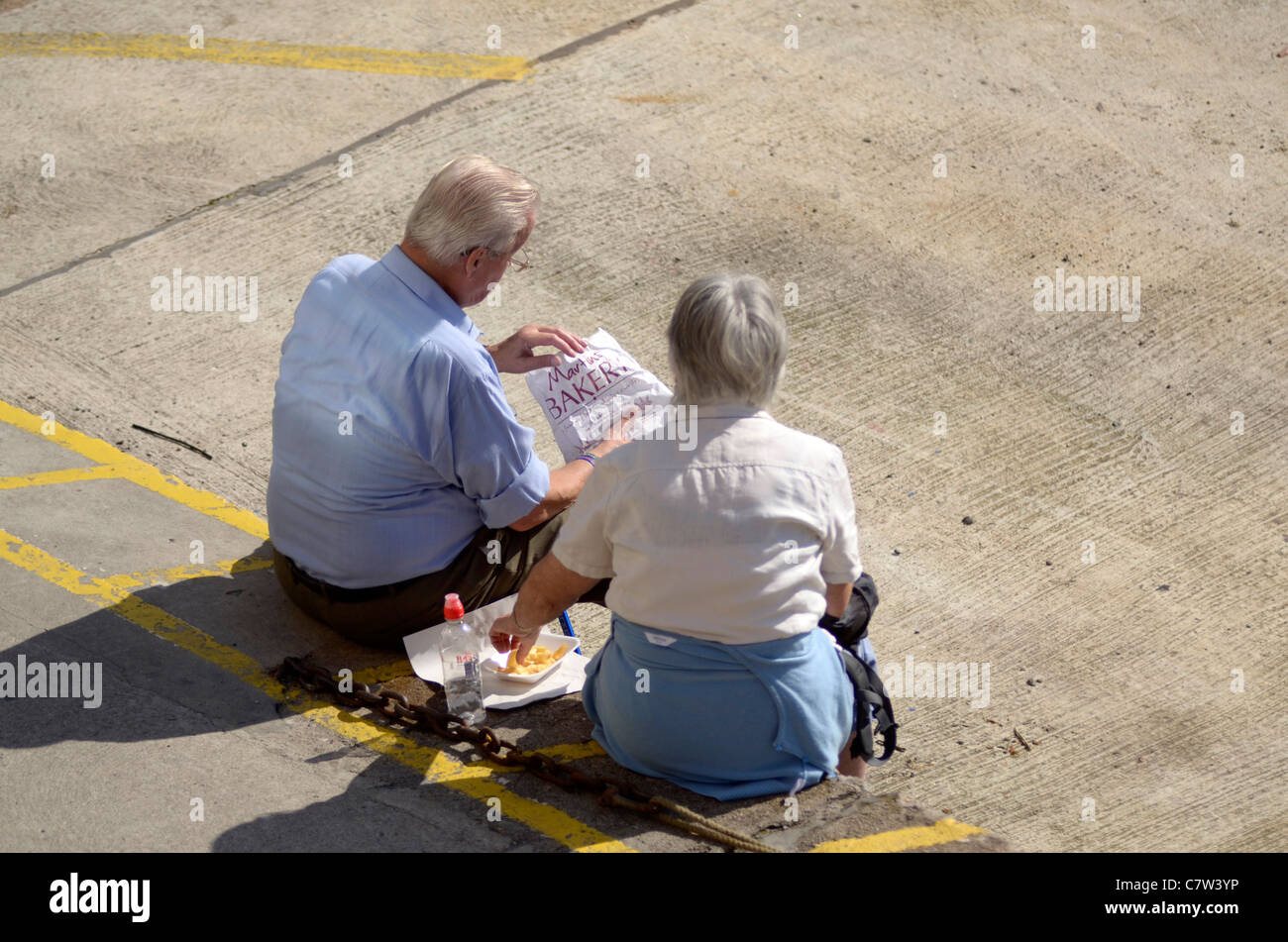 Ehepaar im Ruhestand Essen Fisch und Chips von Mevagissey Hafen Cornwall UK Stockfoto