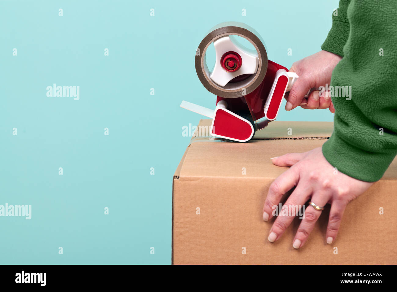 Foto von einem Womans Hände abkleben eine Pappschachtel, eignet sich für Entfernung oder Logistik Themen. Stockfoto