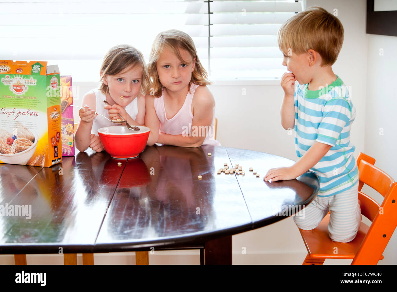 Kinder rund um den Frühstückstisch Stockfoto