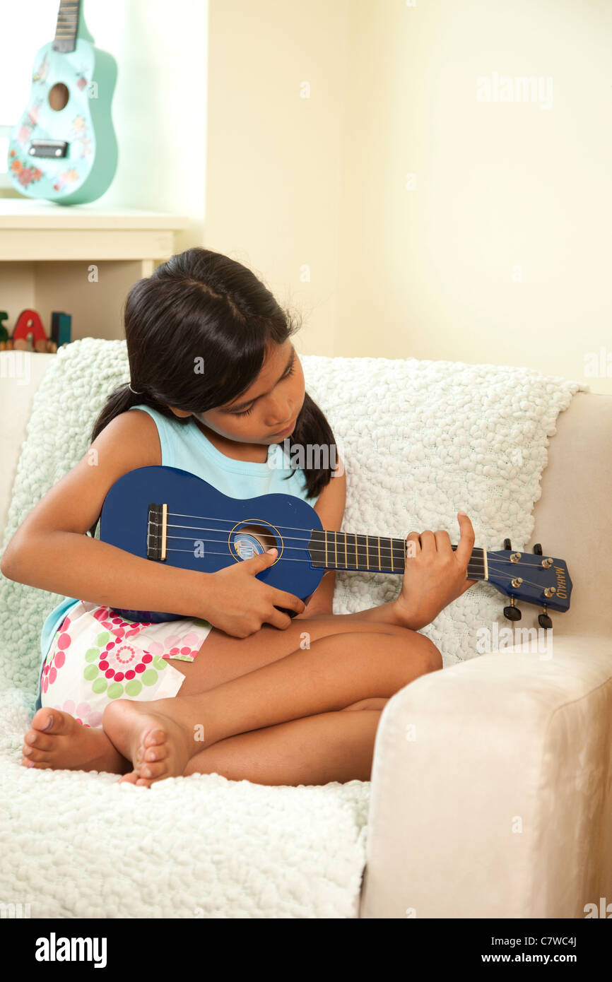 Kleines Mädchen sitzt im Stuhl, Gitarre spielen Stockfoto