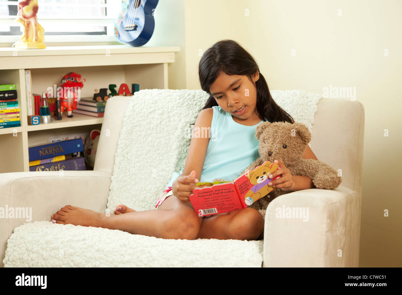 Kleines Mädchen sitzt im Stuhl mit Teddy Teddybär Stockfoto