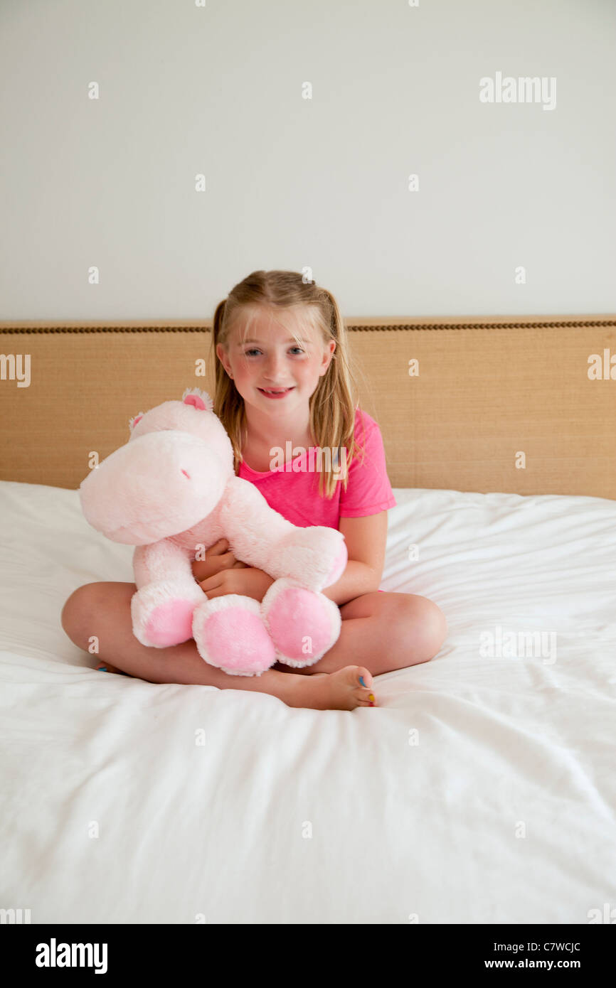 junges Mädchen auf dem Bett mit Stofftier Stockfoto