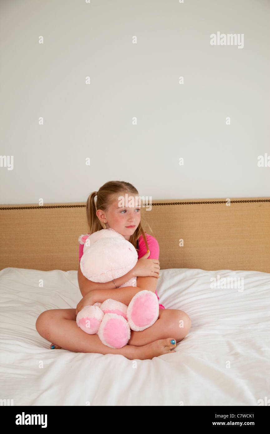 junges Mädchen auf dem Bett mit Stofftier Stockfoto