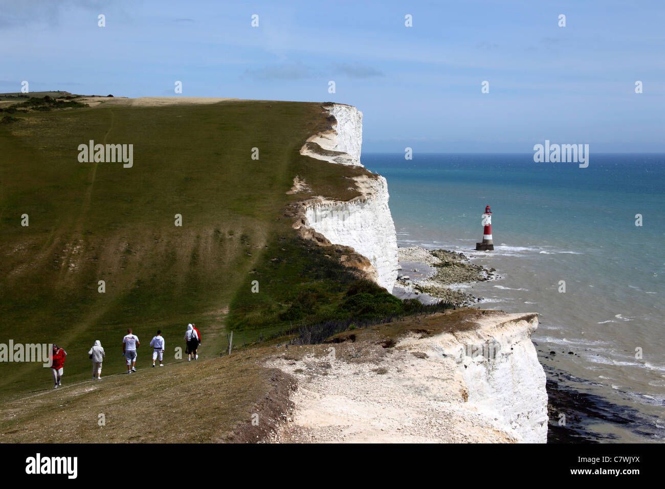 Wanderer zu Fuß entlang der South Downs Way Küste Weg, Beachy Head Leuchtturm im Hintergrund, in der Nähe von Eastbourne, East Sussex, England Stockfoto